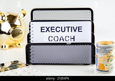 Geschäftskonzept. Der Satz, der Text, das Wort EXECUTIVE COACH sind auf einem weißen Blatt in einem Ständer auf hellem Hintergrund geschrieben. Stockfoto