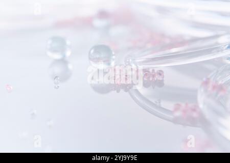 Mehrere Glaskörner, Glaskugeln und Glasringe auf einer reflektierenden Platte Stockfoto