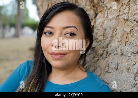Porträt einer Frau, die sich auf einen Baumstamm stützt. Stockfoto