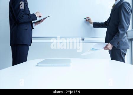 Zwei Männer, die dem Whiteboard zugewandt sind Stockfoto