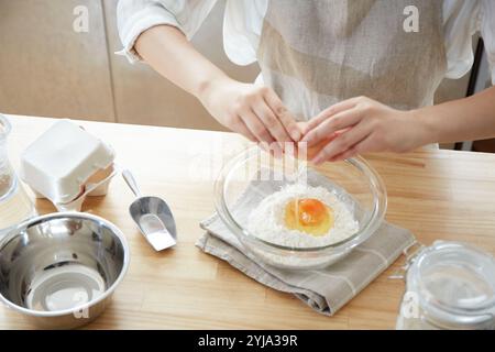 Frau knackt Eier an der Küchentheke Stockfoto