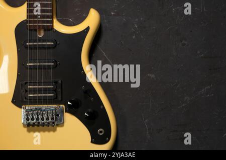 Gelbe E-Gitarre liegt auf einem dunklen Betonhintergrund. Draufsicht mit Platz für Ihren Text. Stockfoto