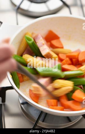 Frauenhand macht eine Gemüsepfanne Stockfoto