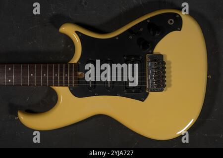Gelbe E-Gitarre liegt auf einem dunklen Betonhintergrund. Draufsicht. Stockfoto