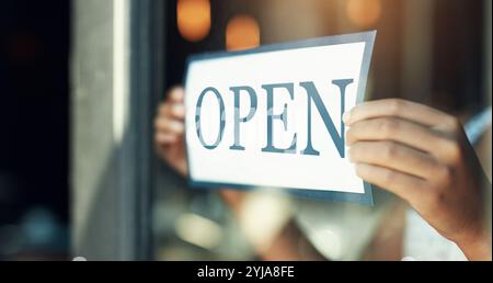 Hände, offenes Schild und Person im Café, kleines Geschäft und Fenster mit Poster, Handelszeiten und Glas. Nahaufnahme, Mitarbeiter und Unternehmer mit Vertrieb Stockfoto