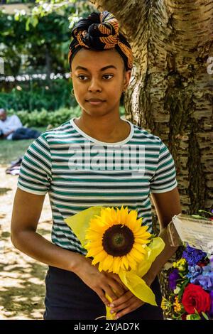 London, Großbritannien. August 2018. Eine Frau posiert mit einer Sonnenblume am Ende der Londoner CND-Zeremonie zum Gedenken an die Opfer, Vergangenheit und Gegenwart, am 73. Jahrestag des Abwurfs der Atombombe auf Hiroshima, und erinnert sich auch an diejenigen, die getötet wurden und mit den Auswirkungen der Strahlung der zweiten Atombombe leben, die drei Tage später auf Nagasaki abgefeuert wurde. Die Reden beinhalteten eine Lektüre der Erklärung, die früher am Tag bei der Gedenkfeier in Hiroshima abgegeben wurde, und einen Appell von Rebecca Johnson, einer der Gründer von ICAN, die den Friedensnobelpreis 2017 für ihre Arbeit an der Schaffung der UNO erhielt Stockfoto