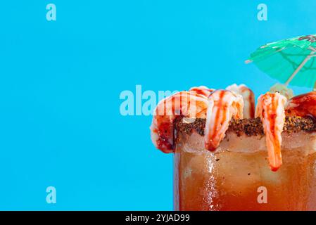 Michelada dekoriert mit Garnelen auf blauem Hintergrund. Kopierbereich. Stockfoto