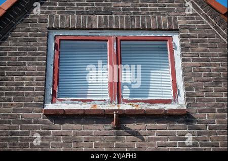 Braunes Ziegelhaus mit roten Fensterrahmen Stockfoto