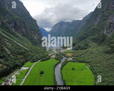 Blick über die Drohne auf den Nærøyfjord mit dem Dorf Gudvangen und seinem ruhigen Wasser, das zwischen den steilen Bergen mit üppiger Vegetation verschwindet Stockfoto