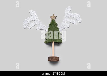 Rentiergesicht aus Papierhörnern und dekorativem Weihnachtsbaum auf weißem Hintergrund Stockfoto