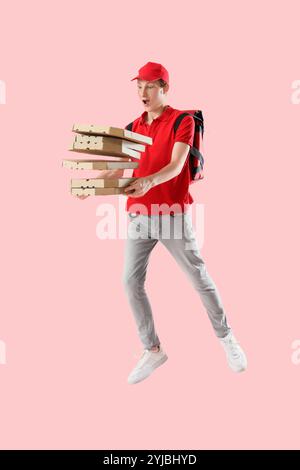 Springender Kurier mit Pizzakartons auf rosa Hintergrund Stockfoto