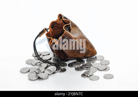 Stapel Silbermünzen um eine leere Ledertasche. Isoliert auf weißem Hintergrund. Studiofoto. Stockfoto