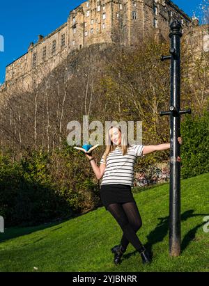 Edinburgh, Schottland, Großbritannien, 14. November 2024, Push the Boat Out: Die preisgekrönte Folk-Sängerin Iona Fyfe posiert mit einem Origami-Papierboot unter dem berühmten Edinburgh Castle, um Schottlands nationales Poetry-Festival zu fördern. Iona wird einen Abend mit Poesie-verschmolzenen Liedern in die Hauptrolle nehmen. Quelle: Sally Anderson/Alamy Live News Stockfoto