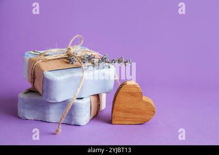 Handgefertigte natürliche Badebad-Spa-Lavendelseife auf violettem Hintergrund. Seifenherstellung. Seifenleisten. Spa, Hautpflege. Geschenkverpackung. Stockfoto