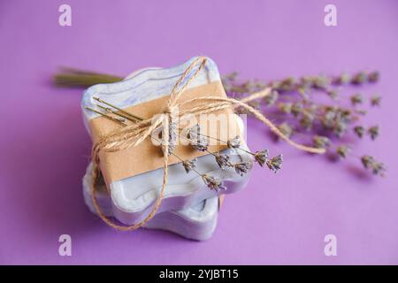 Handgefertigte natürliche Badebad-Spa-Lavendelseife auf violettem Hintergrund. Seifenherstellung. Seifenleisten. Spa, Hautpflege. Geschenkverpackung. Stockfoto