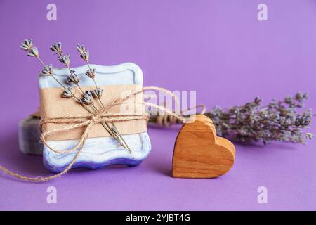 Handgefertigte natürliche Badebad-Spa-Lavendelseife auf violettem Hintergrund. Seifenherstellung. Seifenleisten. Spa, Hautpflege. Geschenkverpackung. Stockfoto