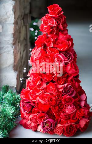 weihnachtsbaum aus einer großen Gruppe von rotem Papier rosen in der Nähe eines Fensters Stockfoto