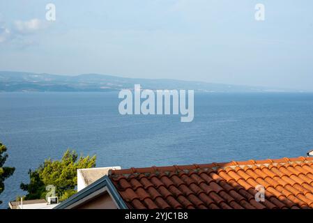 Sonniger Tagesblick auf die Adria über den roten Ziegeldächern in Stanici, Kroatien, der den Charme der Küste einfängt. Stockfoto