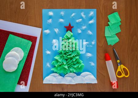 HEIMWERKER Weihnachtsbaum. Einfaches Basteln für Kinder. Winterkarte Weihnachtsbaum aus Papier, zerknittertes Papier, Servietten, Baumwollscheibe. Stockfoto