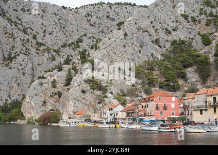Blick auf die Stadt Omis vom Fluss Cetina, Kroatien, mit dem malerischen Fluss, der durch das Tal fließt, umgeben von zerklüfteten Bergen und dem Saibling der Stadt Stockfoto