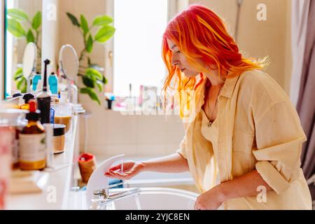 Junge Frau mit lebendigen Haaren in modernem Badezimmer Stockfoto