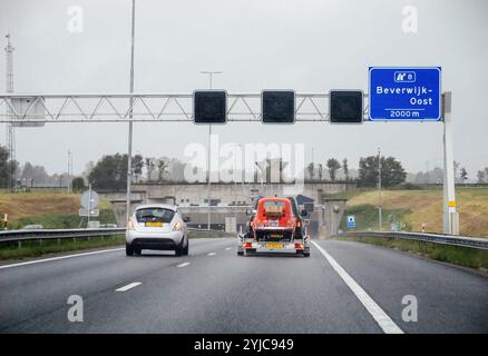Den Helder, Niederlande - 24. August 2024: Blick von einem Auto auf einer niederländischen Autobahn in Richtung Beverwijk-Oost, mit Verkehr und einem Schild, das die bevorstehende Ausfahrt anzeigt, an einem regnerischen Tag. Stockfoto