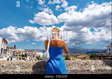 Eine Frau in blauem Kleid genießt die Aussicht auf Rondas Landschaft und den historischen Charme Stockfoto