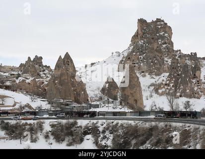 UCHISAR, NEVSEHIR, TÜRKEI-04. FEBRUAR 2017: Ruinen der Festung Uchisar mit Menschen auf der Spitze, Feenkamine und Souvenirläden an der Straße Stockfoto