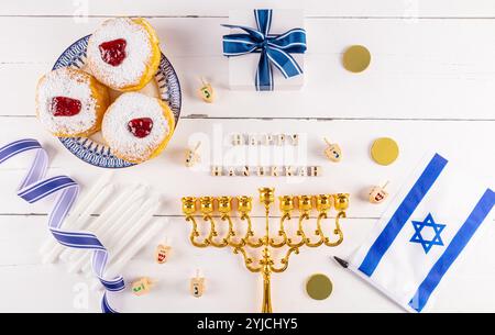 Eine festliche Kulisse für die jüdische Hanukka. Blick von oben auf einen weißen Holztisch mit traditionellen Symbolen, Leckereien für den Urlaub. Der Text des Wunsches Stockfoto