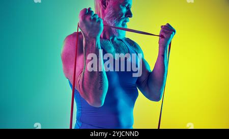 Nahaufnahme eines muskulären Seniorentrainings mit Widerstandsband gegen grün-gelbem Hintergrund im Neonlicht Stockfoto