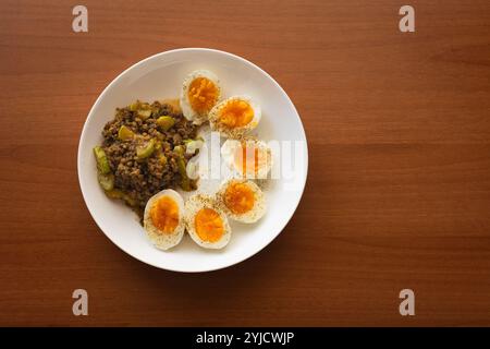 Nahaufnahme von gekochten Eiern, weiß mit gelbem Eigelb, in Hälften geschnitten, auf einem weißen Teller mit gekochtem Rindfleisch. Gesunde Ernährung, Low Carb Diät. High Pro Stockfoto