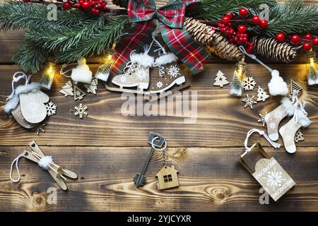 Hausschlüssel mit Schlüsselanhänger Cottage auf festlichem, umweltfreundlichem, natürlichem Hintergrund mit Weihnachtsbaum. Frohes neues Jahr, roter Hintergrund, Geschenk, Grußkarte. Stockfoto