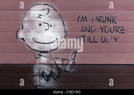 Cartoon Charlie Brown aus den Peanuts mit einer Flasche Alkohol, ich bin betrunken und du bist immer noch hässliches, ironisches Graffiti von Street Artist L.E.T., Ur Stockfoto