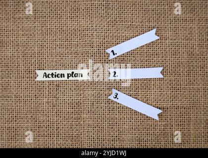Notizpapier mit den Worten „Aktionsplan“ und leere Papierstücke mit den Nummern 1, 2 und 3 sind so angeordnet, dass sie Schritte oder Phasen vorschlagen. Stockfoto