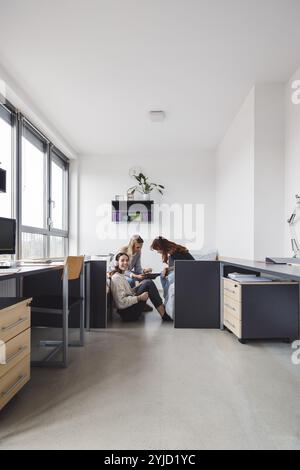 Gruppe von drei Mitbewohnern, College Studentin, junge kaukasische Frauen, verbringen Zeit zusammen in ihrem Zimmer, lernen, reden, Spaß haben, lachen Stockfoto