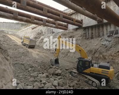 Bagger und Muldenkipper arbeiten auf einem Schotterweg auf einer Baustelle Stockfoto