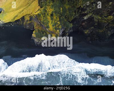 Vulkanischer schwarzer Sandstrand mit Blick auf Reynisdrangar. Wellen krachen am schwarzen Sandstrand. Vik, Island. Stockfoto
