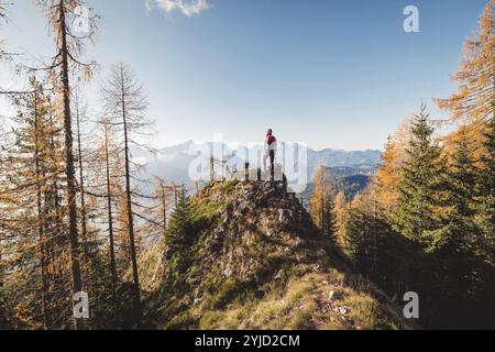 Malerische Aussicht auf den Herbstberg, die europäischen Alpen, von einem Aussichtspunkt, wo die kaukasische Wandererin steht. Die Sonne scheint hoch oben in den Bergen, A Stockfoto