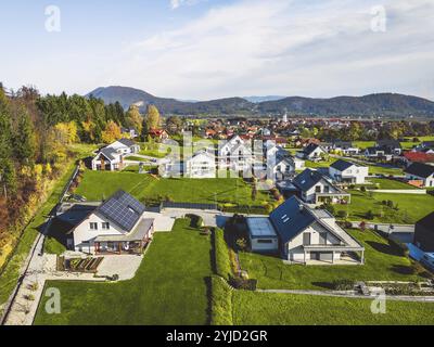 Luftaufnahme, Drohne fliegt über neue Wohnsiedlungen auf der Landseite. Einfamilienhäuser in den Vororten umgeben von Wald und grünen Feldern Stockfoto