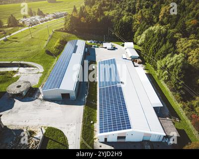 Solarpaneele, die auf dem Dach eines großen Industriegebäudes oder eines Lagers installiert sind. Industriegebäude auf der Landseite Sloweniens mit Wohnhaus h Stockfoto