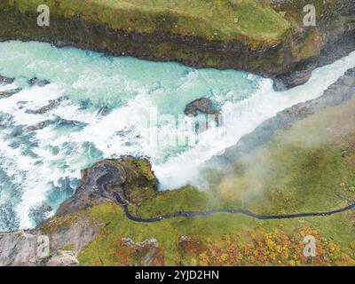 Riesiger, schöner Wasserfall Gullfoss, berühmtes Wahrzeichen in Island. Der Fluss schäumt, während er den Wasserfall herunterfällt, Touristen gehen vorbei und schauen sich das Wasser an Stockfoto