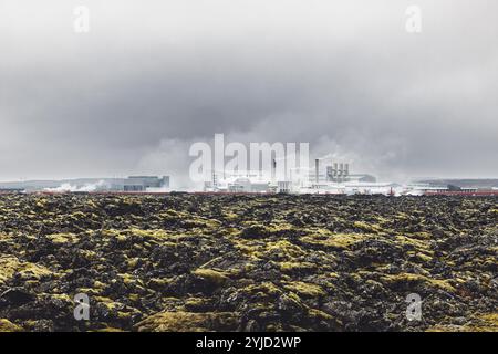 Geothermiekraftwerk, Warmwasserkraftwerk in Island. Dampf, der aus den Schornsteinen der Anlage herausgerollt wird, rote große Rohre, die über das Gelände laufen, gefüllt Stockfoto