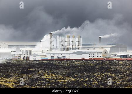 Geothermiekraftwerk, Warmwasserkraftwerk in Island. Dampf, der aus den Schornsteinen der Anlage herausgerollt wird, rote große Rohre, die über das Gelände laufen, gefüllt Stockfoto