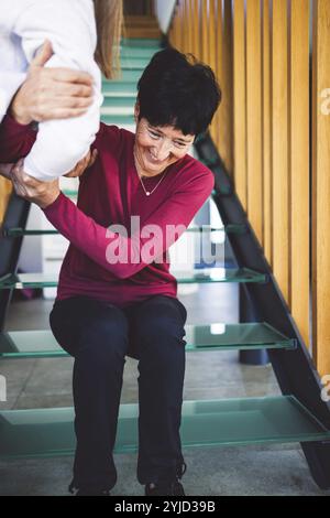 Junge kaukasische Frau, Krankenschwester, bei einem Hausbesuch, um eine Seniorin zu versorgen. Die Schwester hilft einer Seniorin bei den täglichen Aufgaben, hilft ihr, zu laufen Stockfoto