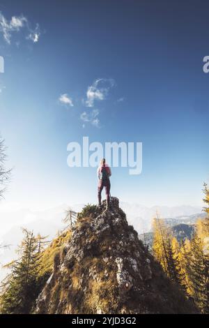 Malerische Aussicht auf den Herbstberg, die europäischen Alpen, von einem Aussichtspunkt, wo die kaukasische Wandererin steht. Die Sonne scheint hoch oben in den Bergen, A Stockfoto