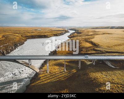 Hellblauer Fluss unter der Brücke durch das isländische Festland im Herbst an einem kalten Tag. Stockfoto