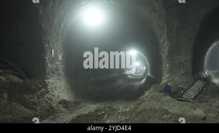 Beleuchteter unterirdischer Tunnel im Bau mit schweren Maschinen und hellen Lichtern Stockfoto