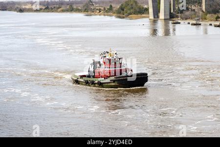 Savannah, Georgia, USA - 20. Februar 2024: Ein Schlepper fährt stetig durch den Fluss und fährt an sonnigen Tagen um Brücken. Stockfoto