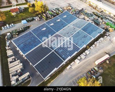 Aus der Vogelperspektive einer Fabrik, einer Lagerhalle in den Vororten mit Dach, das mit Solarpaneelen bedeckt ist. Stockfoto