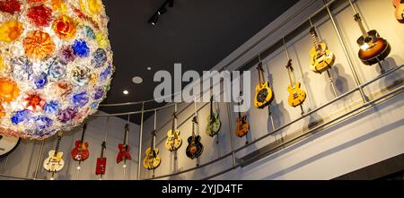 Savannah, Georgia, USA - 20. Februar 2024: Eine lebendige Sammlung von E-Gitarren hängt an der Wand, beleuchtet von einem künstlerischen Kronleuchter. Stockfoto